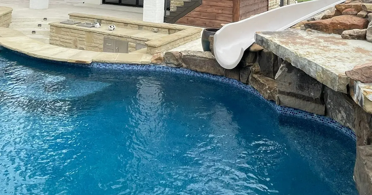Freeform pool edged with natural stone boulders and a large flat stone ledge